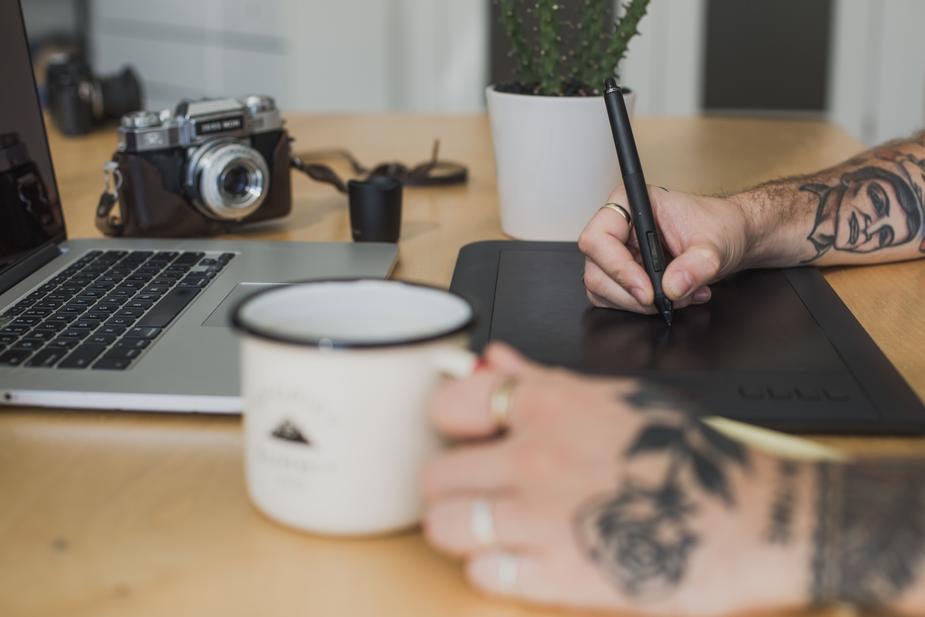 Designer uses a sketch pad while holding a cup of coffee